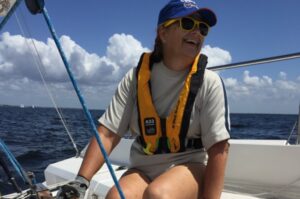 Happy woman steering a Colgate 26 in Offshore Sailing School Learn to Sail 101 course in Florida