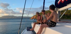Three young boys talking to each other while sitting on a big cruising boat in the British Virgin Islands
