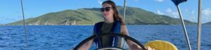 A young woman in at the helm of a monohull cruising boat, in Family Fast Track to Cruising Course in the British Virgin Islands