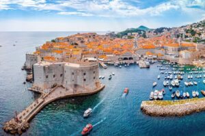 Aerial shot of Dubrovnik Harbor with many boats and lots of red roofs of old town on Croatia flotilla cruise