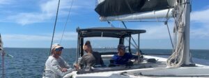 Two men with an Offshore Sailing School instructor in cockpit of a 45' sailing catamaran