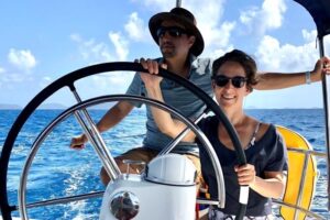 Man and woman on a sailboat. Woman steering.